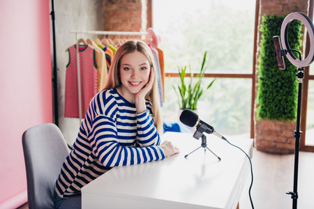 Profile portrait of nice young girl toothy smile smart phone holder record blog video background home studio indoorsの写真素材