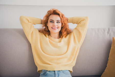 Photo of positive good mood woman dressed yellow sweater sitting arms behind head indoors house...