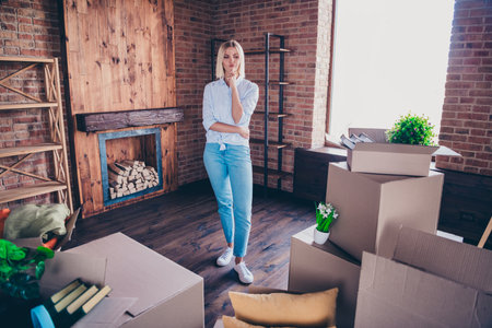 Full length photo of cheerful girl thoughtful suspicious look carton boxes dressed shirt jeans move...