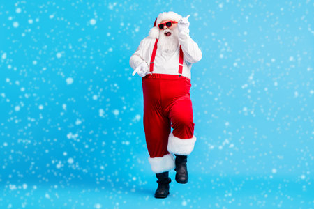 Full size photo of funky fat santa claus with big abdomen beard dance x-mas christmas holly party club wear suspenders overalls sunglass boots isolated blue color backgroundの写真素材