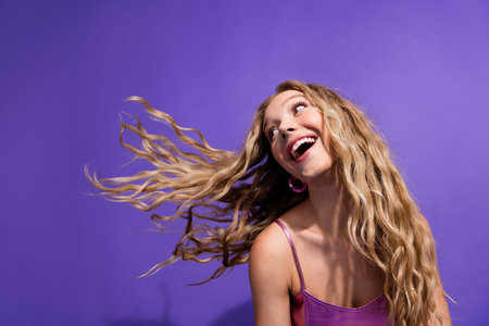 Photo of pretty young girl look empty space flying hair wear shiny top isolated on violet color backgroundの写真素材