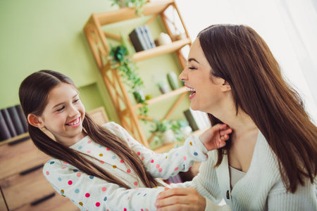 Joyful bonding moment between young mother and daughter enjoying a spring day indoorsの写真素材
