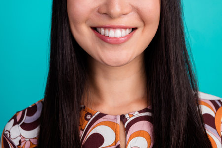 Close up cropped portrait of nice young girl toothy smile isolated on turquoise color backgroundの写真素材
