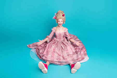 Photo of gorgeous cheerful lady wear pink gown corset fall down floor isolated on blue color backgroundの写真素材