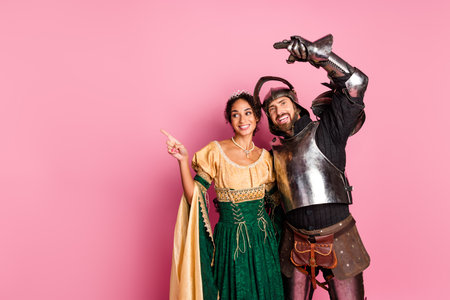 Young couple dressed in medieval knight and princess costumes on a pink background, themed party conceptの写真素材