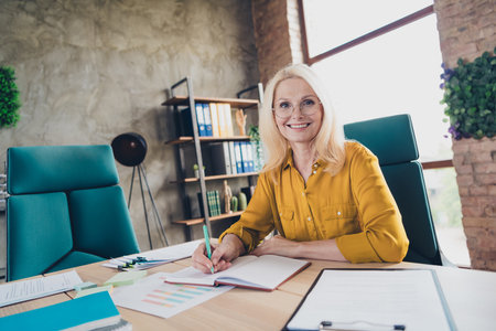 Photo of sweet charming lady assistant wear shirt writing notes copybook indoors workplace workstationの写真素材