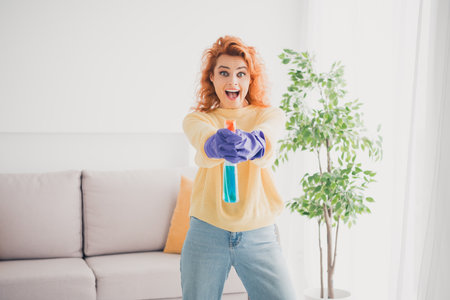 Photo of adorable sweet lady wear yellow sweatshirt doing cleaning shooting you spray indoors room home houseの写真素材