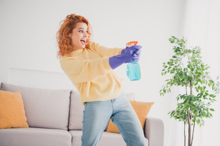 Photo of positive good mood woman dressed yellow sweater doing clean up shooting spray indoors house apartment roomの写真素材