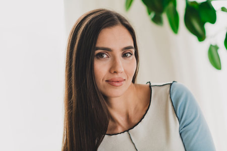 Charming Young Woman Indoors in a Casual Outfit with Natural Daylight in a Comfortable Interior for Lifestyle and Fashion Scenesの写真素材