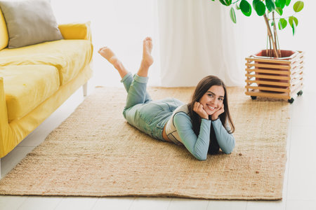 Young woman relaxing on a rug in a cozy stylish interior with daylightの写真素材