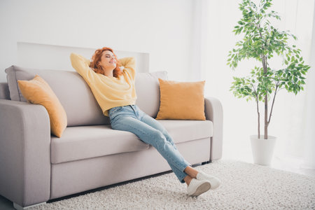 Photo of pretty cheerful lady wear yellow pullover having rest arms behind head indoors room home...