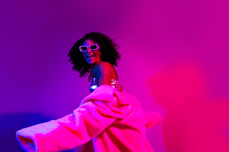 Young stylish woman wearing fashion attire with glowing neon effects and vibrant retro colors in a...