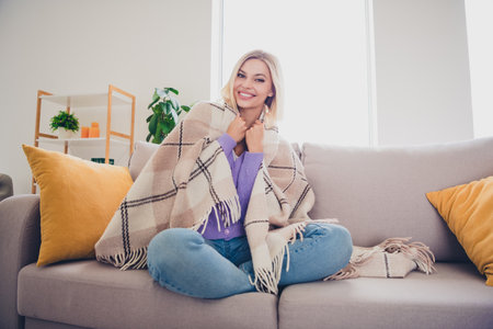 Charming young woman with blond hair relaxing indoors on a cozy weekend afternoonの写真素材