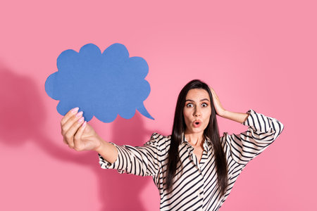 Young woman in striped shirt expressing surprise with blue speech bubble against pink background