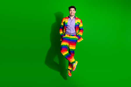 Young Man in a Vibrantly Colored Suit Posing Joyfully Against a Bold Green Background, Representing Creativity, Pride, and Funの写真素材