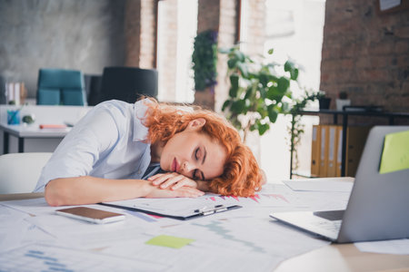 Portrait of young corporate worker lady sleep desk modern loft interior business center indoorsの写真素材