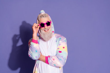 Trendy man in unicorn pajama posing against vibrant violet background, exuding happiness and styleの写真素材