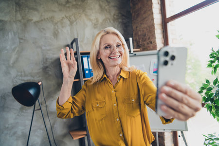 Photo of adorable positive lady broker wear shirt waving arm recording video modern device indoors workplace workshopの写真素材