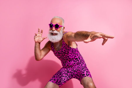 Photo of positive old man dancing have fun wear glamour leopard print overall isolated pink color backgroundの写真素材