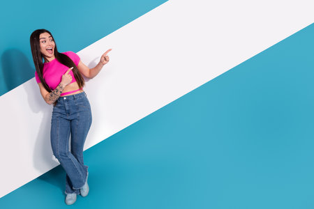 Young Woman Posing in Casual Style with a Cheerful Gesture on a Blue Background, Perfect Visual for Advertising or Promotingの写真素材