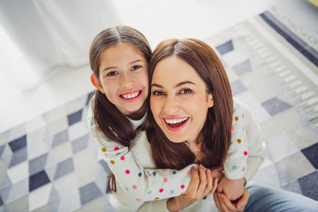 Happy young mother and daughter bonding at home on a bright spring dayの写真素材