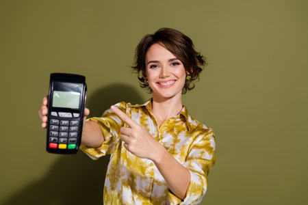 Confident young businesswoman promoting card reader for modern shopping solutions, wearing elegant...