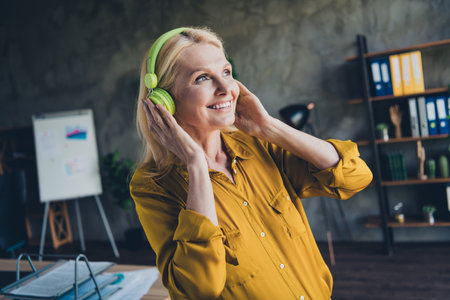 Photo of adorable positive lady broker wear shirt listening headphones indoors workplace workshopの写真素材