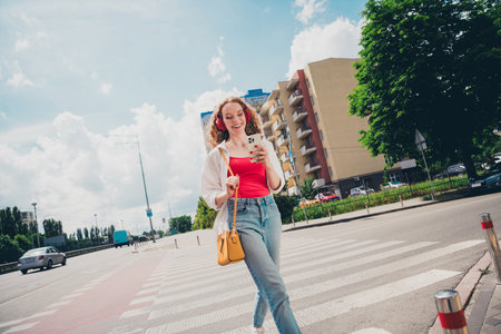Photo of pretty sweet woman earphones cross road hold device dressed white shirt outdoors urban...