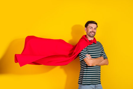 Confident Man in Striped Shirt and Red Cape Posing Against Bright Yellow Background, Representing Strength, Styleの写真素材