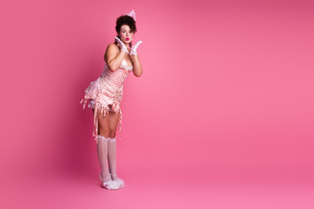 A young woman in an elegant, vintage-inspired corset dress, set against a vibrant pink background