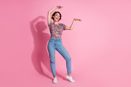 Photo of cheerful adorable cute girl wear trendy print outfit dance isolated on pink color backgroundの写真素材