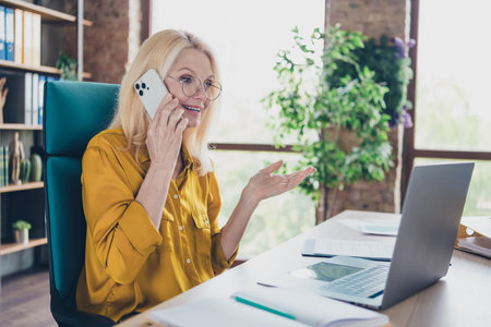 Photo of happy excited lady ceo dressed shirt communicating modern gadget indoors workplace workstation loftの写真素材