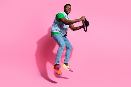 Energetic young man jumping with joy against a vibrant pink background, showcasing modern style with...