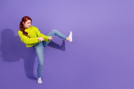 Young red-haired woman in green sweater gesturing playfully against a vibrant purple backdrop