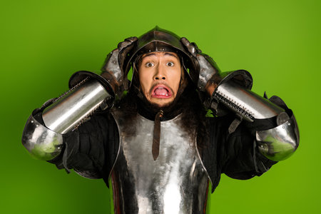 Amusing Young Male in Medieval Armor Against a Bright Green Backgroundの写真素材