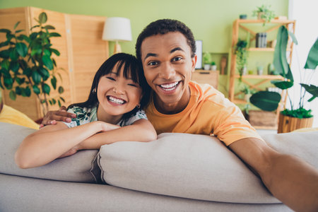 Photo of cheerful cute couple wear t-shirts weekend time together indoors house living room apartment flatの写真素材