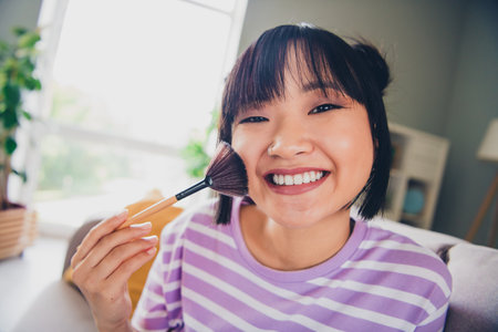 Photo of adorable sweet lady wear violet striped t-shirt aplying countouring indoors room home houseの写真素材