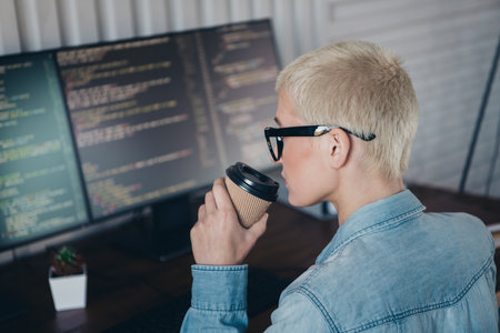 Blond Woman Working on Programming Tasks From Home Office with a Casual Styleの写真素材