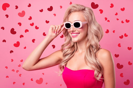 Portrait of cute lovely girl toothy smile arm touch sunglass empty space ad isolated on pink color backgroundの写真素材