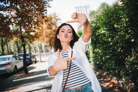 Young woman enjoying a sunny day on an urban street wearing a stylish shirt and casual clothes, having fun outdoorsの写真素材