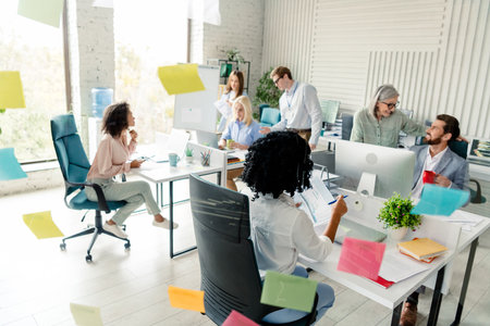 Diverse team collaborating in modern workplace with cheerful atmosphere and daylightの写真素材