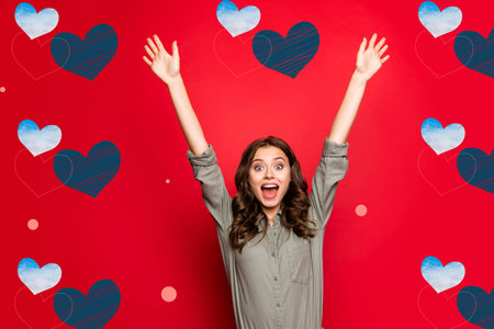 Portrait of cheerful, carefree lady in blouse or shirt, with brunette modern curly hairstyle raised palms up and open mouth isolated on vivid red backgroundの写真素材