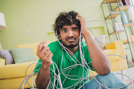 Photo of young man hold tied wire wear t-shirt modern green interior apartment indoorsの写真素材