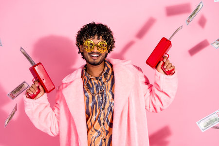 Young stylish man in vibrant attire showcasing a playful lifestyle on a pink background