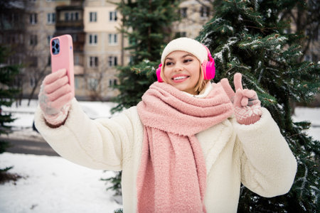 Photo of cheerful charming blogger wear white coat hat scarf warm outwear recording video showing...