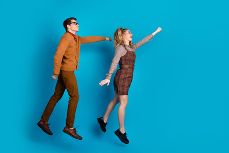 Playful couple posing in stylish casual outfits against a blue backgroundの写真素材