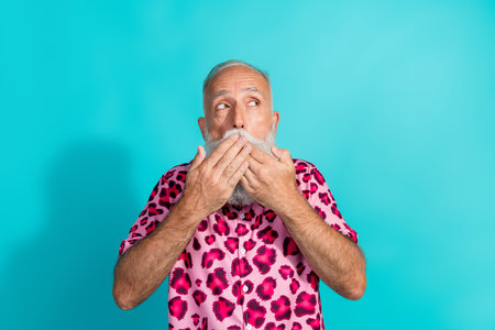 Photo of funny aged man cover mouth look empty space wear leopard print outfit isolated on teal color backgroundの写真素材
