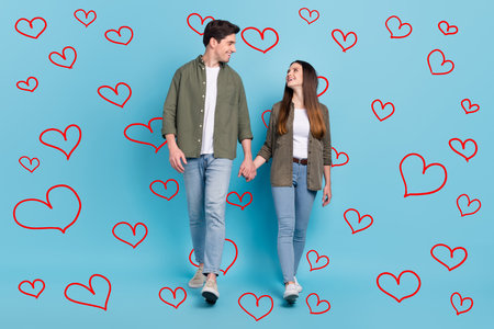 Photo of excited charming young guy woman dressed khaki shirts smiling walking holding arms isolated...
