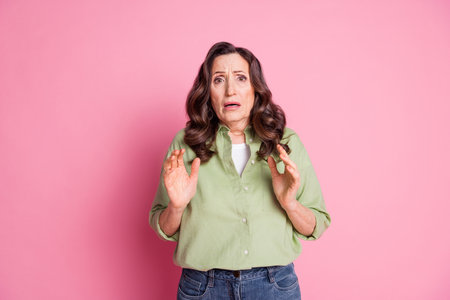 Photo of horrified mature age attractive woman raised hands up shocked looking at scary movie...