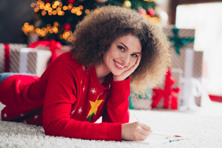 Photo of lovely cute woman lying floor writing plans christmas preparation holidays magic atmosphere new year decorations indoorsの写真素材